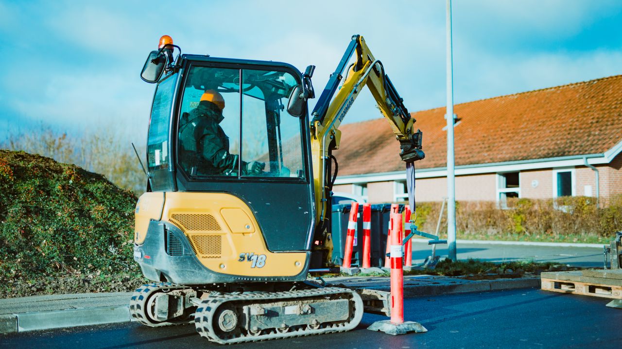 Un mini excavateur en fonctionnement sur un chantier à Odder, au Danemark. Une personne est vue en train de travailler.