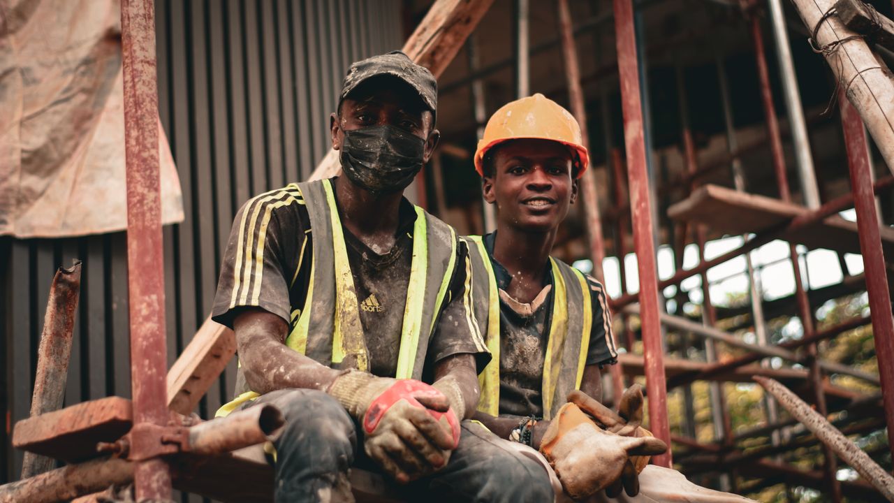 Deux travailleurs de la construction en équipement de sécurité prennent une pause sur un échafaudage sur le site de travail.