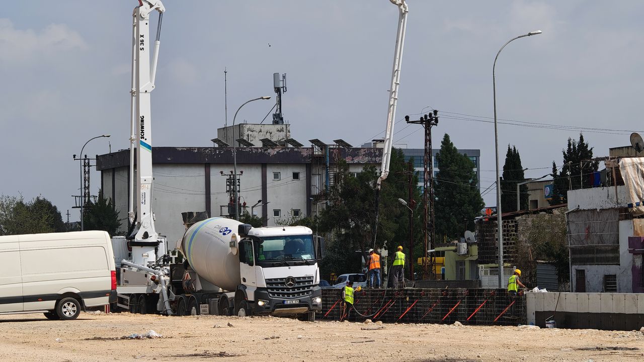 Camions malaxeurs à béton et ouvriers du bâtiment sur un chantier urbain.