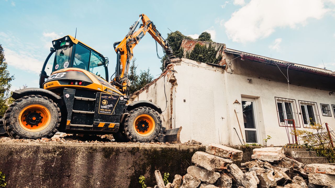 Puissant excavateur en train de détruire une vieille maison lors d'un projet de démolition en extérieur.
