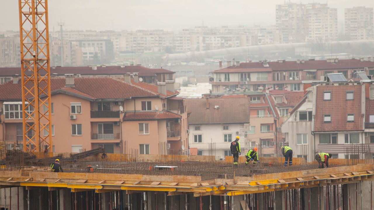 Des ouvriers sur un chantier de construction en ville avec des bâtiments en arrière-plan. Scène de développement urbain industriel.