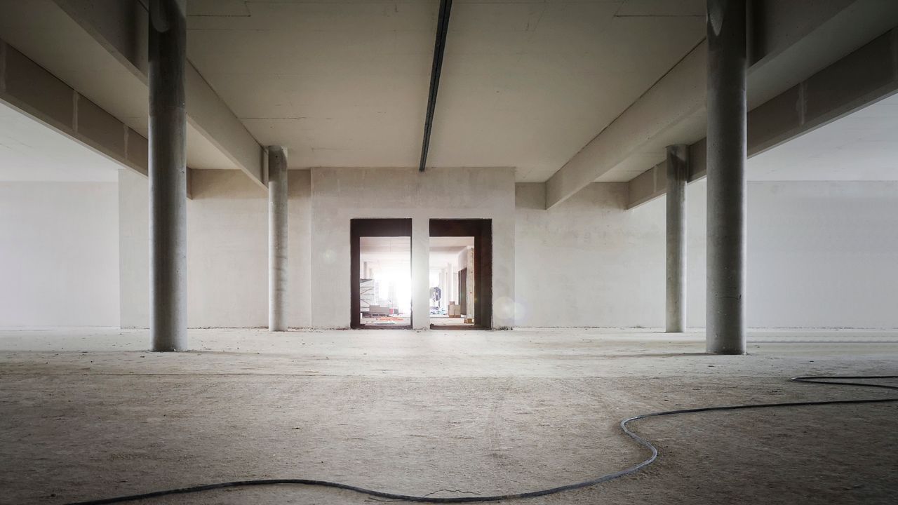 Espace intérieur industriel avec des colonnes en béton et des murs bruts, idéal pour des projets de rénovation.